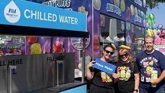 Image4 of four adults standing next to a chilled Water stand at the OC Fair.